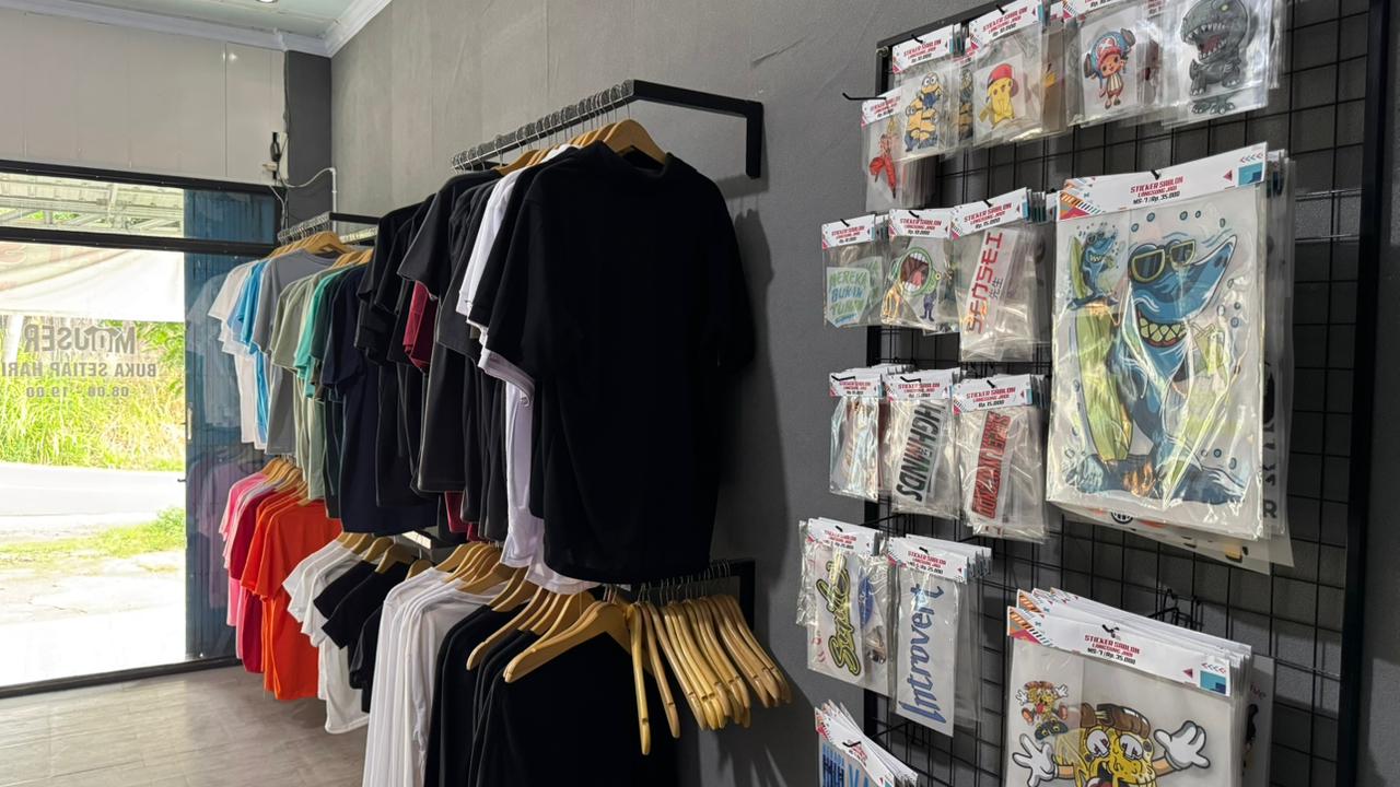 Bagian dalam toko: rak kaos dan display stiker
